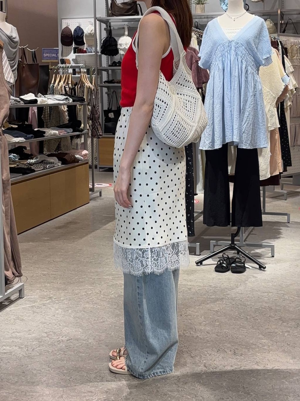 ブルー系のデニムパンツ、ホワイト系のサンダル、レッド系のタンクトップを着用したレディースの春コーディネートの2枚目の写真