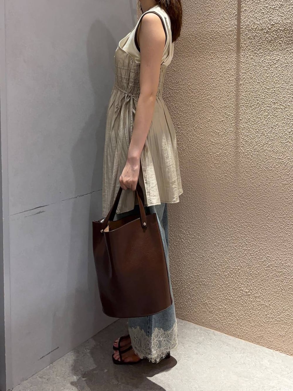 ベージュ系のワンピース、ホワイト系のタンクトップ、ブルー系のデニムパンツを着用したレディースの夏コーディネートの2枚目の写真