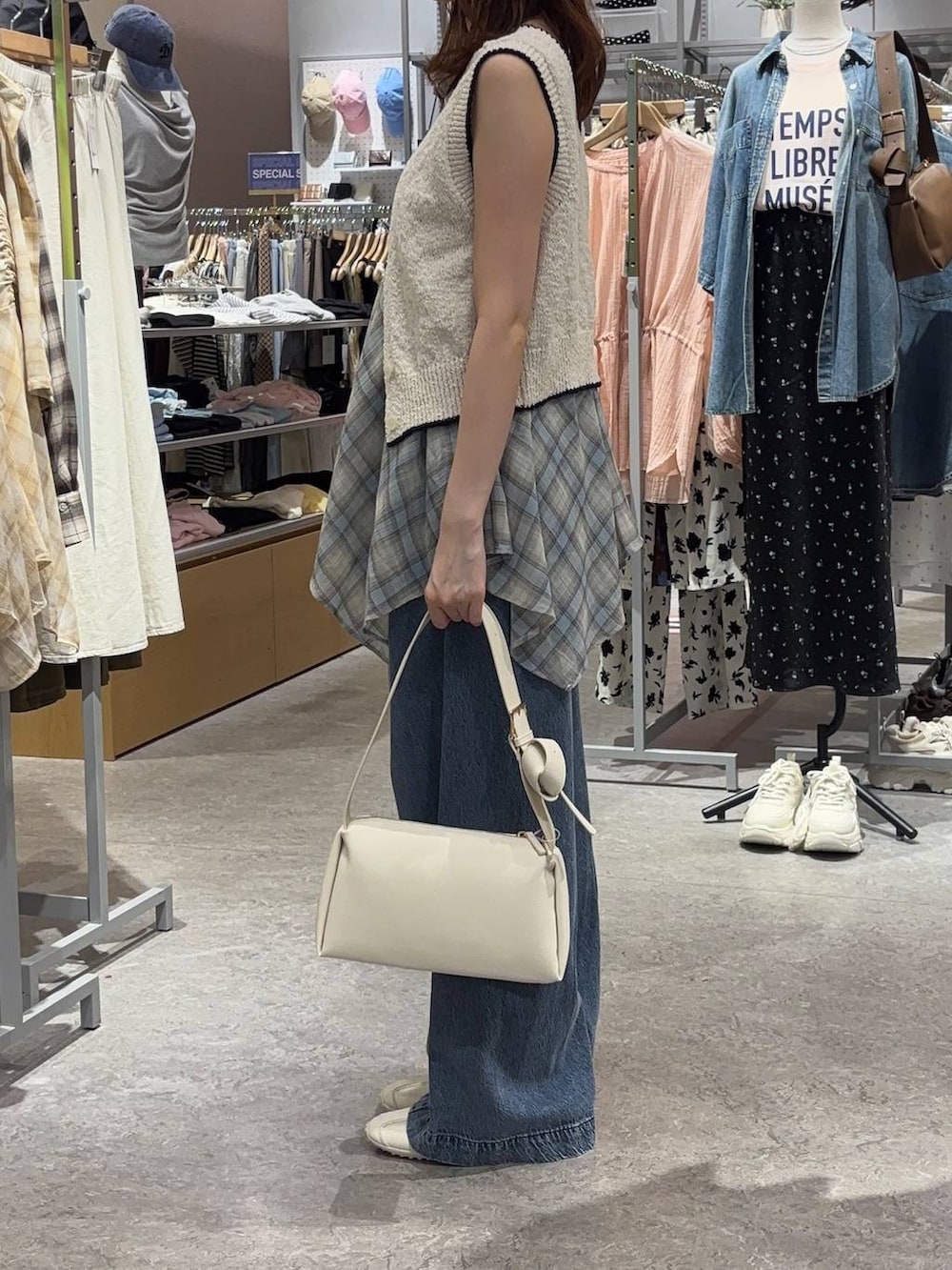 ブルー系のデニムパンツ、ホワイト系のスニーカー、ホワイト系のベストを着用したレディースの春コーディネートの2枚目の写真