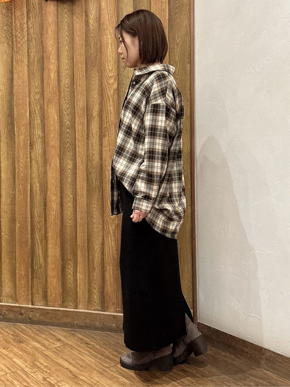 レッド系のニット/セーター、ブラウン系のシャツ/ブラウス、ブラック系のスカートを着用したレディースの秋コーディネートの2枚目の写真