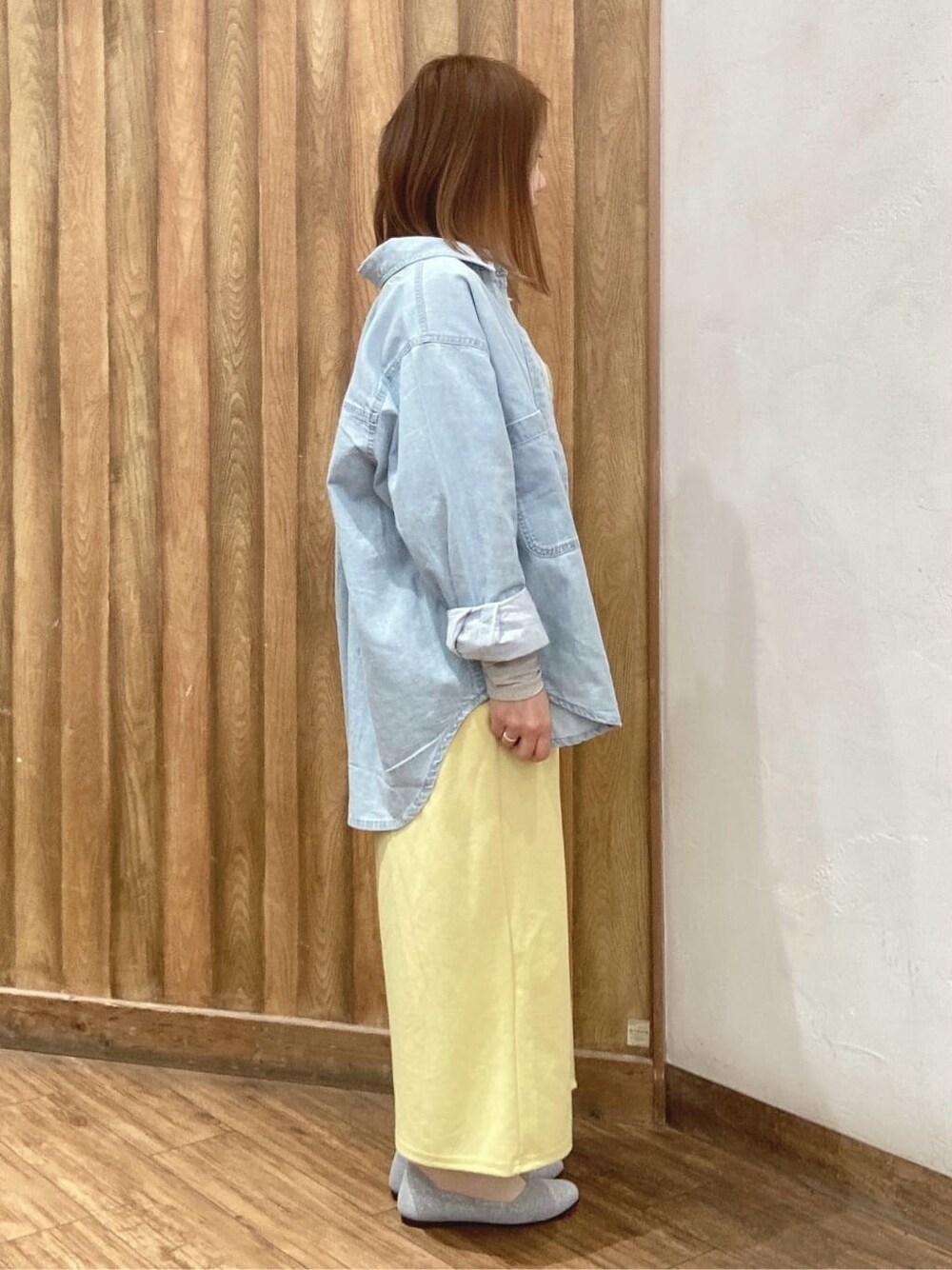 ブルー系のシャツ/ブラウス、グレー系のニット/セーター、イエロー系のスカートを着用したレディースの春コーディネートの2枚目の写真