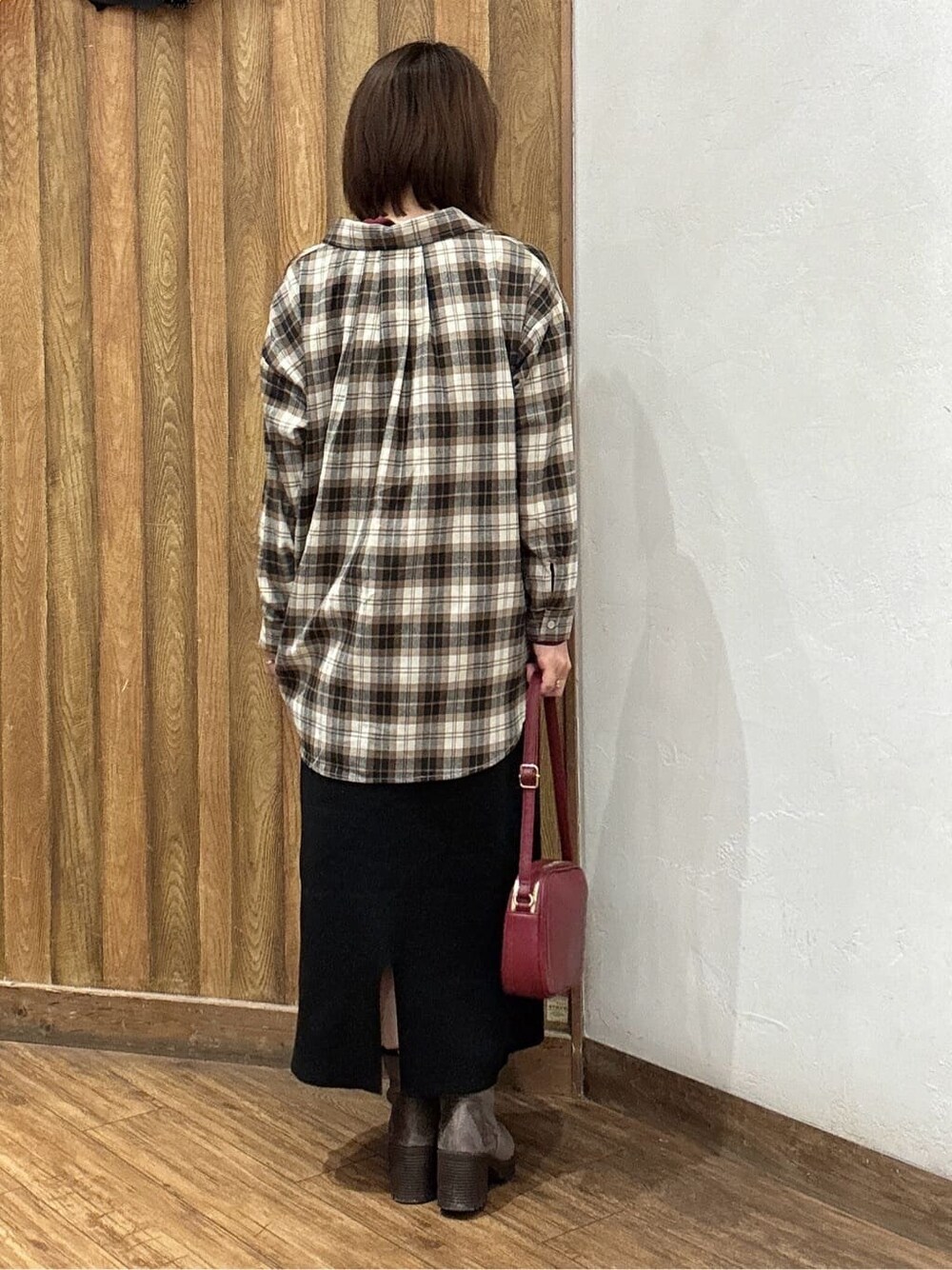 レッド系のニット/セーター、ブラウン系のシャツ/ブラウス、ブラック系のスカートを着用したレディースの秋コーディネートの3枚目の写真