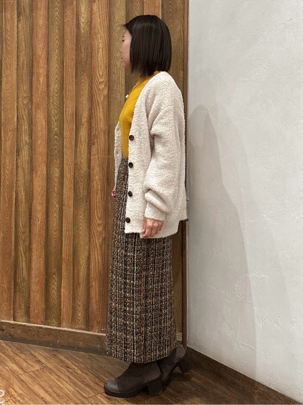 ベージュ系のカーディガン/ボレロ、ブラウン系のスカート、ブラウン系のブーツを着用したレディースの冬コーディネートの2枚目の写真