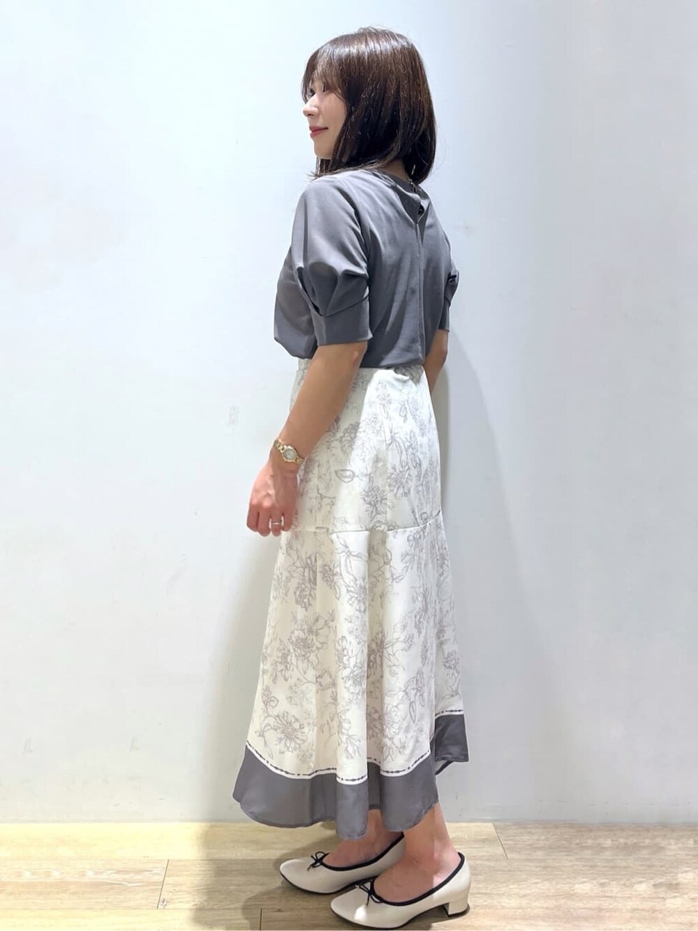 グレー系のTシャツ/カットソー、グレー系のスカート、ベージュ系のパンプスを着用したレディースの秋コーディネートの2枚目の写真