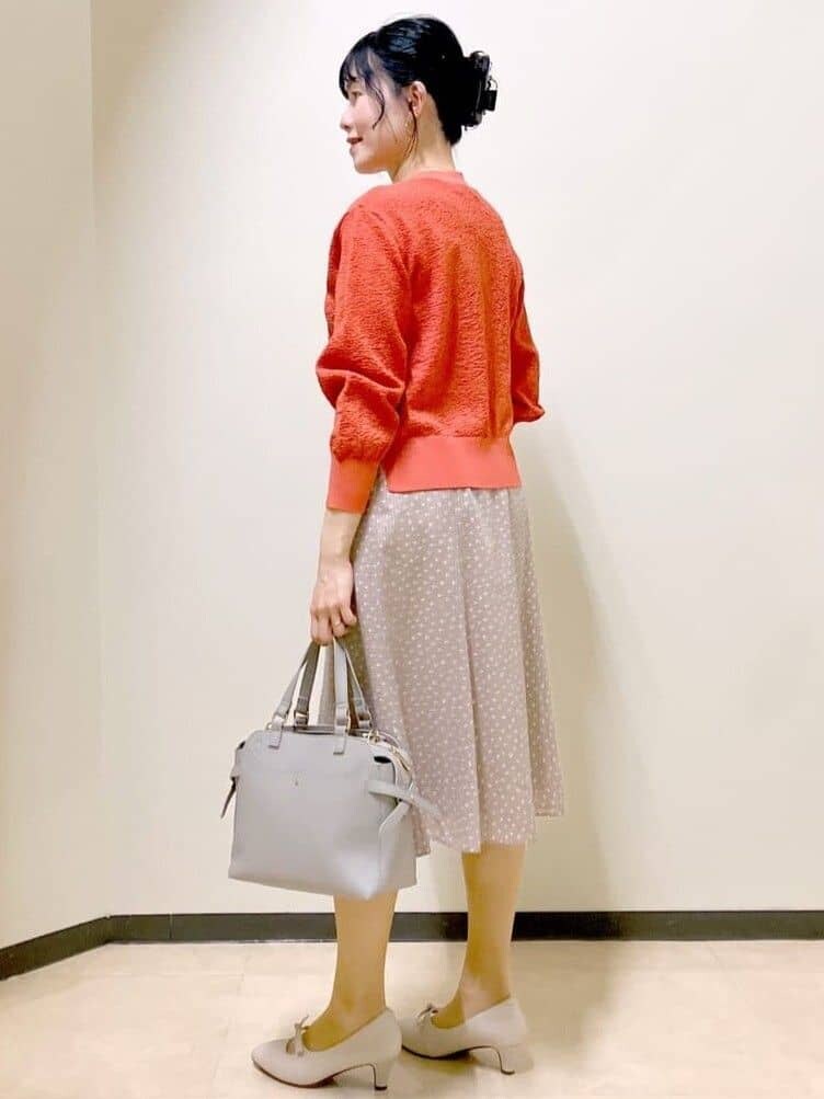 ベージュ系のトレンチコート、オレンジ系のニット/セーター、ブラウン系のスカートを着用したレディースの春コーディネートの9枚目の写真