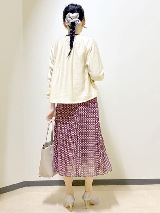 レッド系のスカート、ベージュ系のブルゾン、ベージュ系のトートバッグを着用したレディースの春コーディネートの3枚目の写真