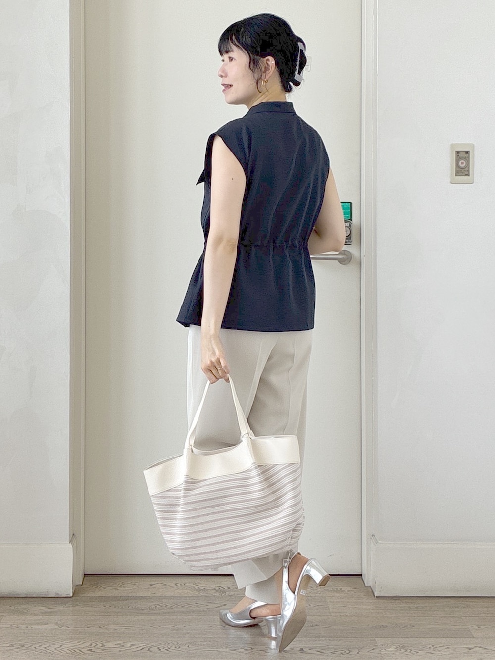 ブルー系のベスト、ベージュ系のその他パンツ、ベージュ系のトートバッグを着用したレディースの春コーディネートの4枚目の写真