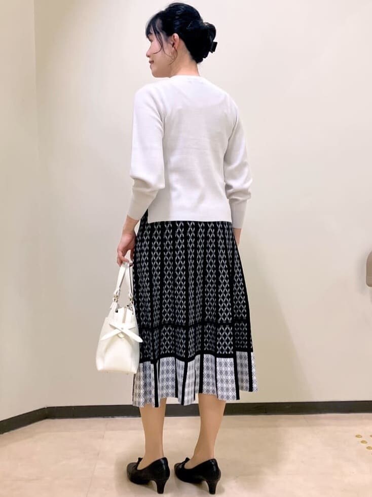 グレー系のニット/セーター、ブルー系のスカート、ホワイト系のトートバッグを着用したレディースの冬コーディネートの4枚目の写真