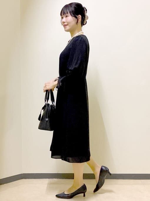 ブラック系のワンピース、ホワイト系のノーカラージャケット、ブラック系のハンドバッグを着用したレディースの冬コーディネートの2枚目の写真
