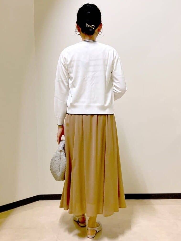ホワイト系のニット/セーター、ホワイト系のカーディガン/ボレロ、イエロー系のスカートを着用したレディースの春コーディネートの3枚目の写真