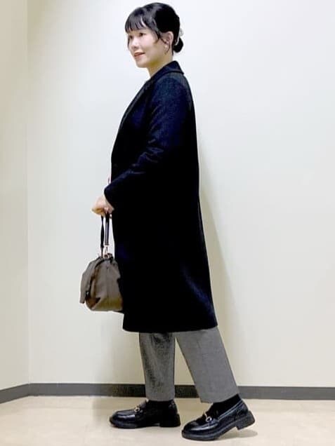 ブラック系のチェスターコート、レッド系のニット/セーター、ホワイト系のTシャツ/カットソーを着用したレディースの冬コーディネートの2枚目の写真
