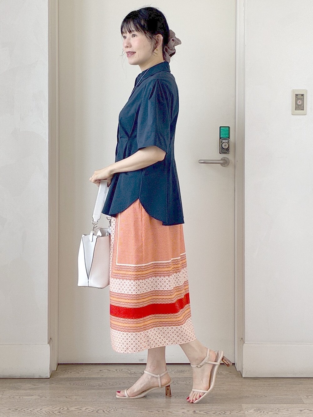 ブルー系のシャツ/ブラウス、オレンジ系のスカート、ホワイト系のトートバッグを着用したレディースの夏コーディネートの2枚目の写真