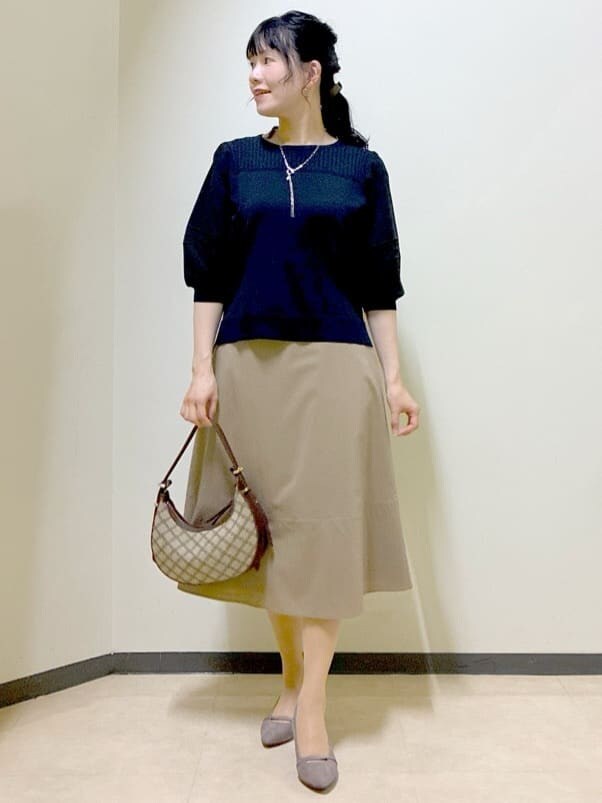 ブルー系のTシャツ/カットソー、イエロー系のスカート、ブラック系のニット/セーターを着用したレディースの秋コーディネートの7枚目の写真