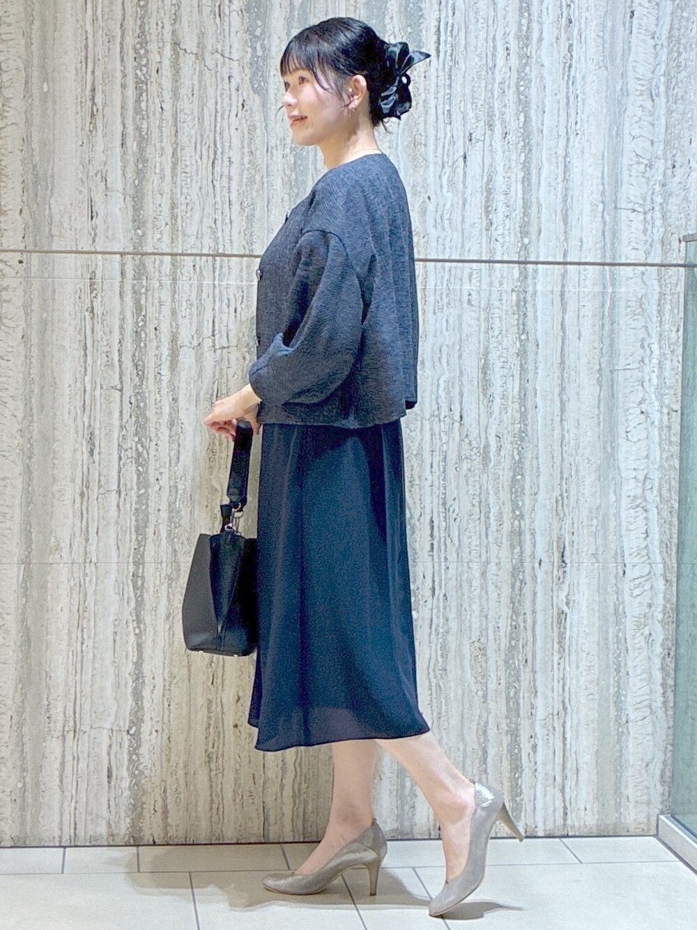 ブルー系のノーカラージャケット、ブルー系のワンピース、ブラック系のトートバッグを着用したレディースの夏コーディネートの2枚目の写真