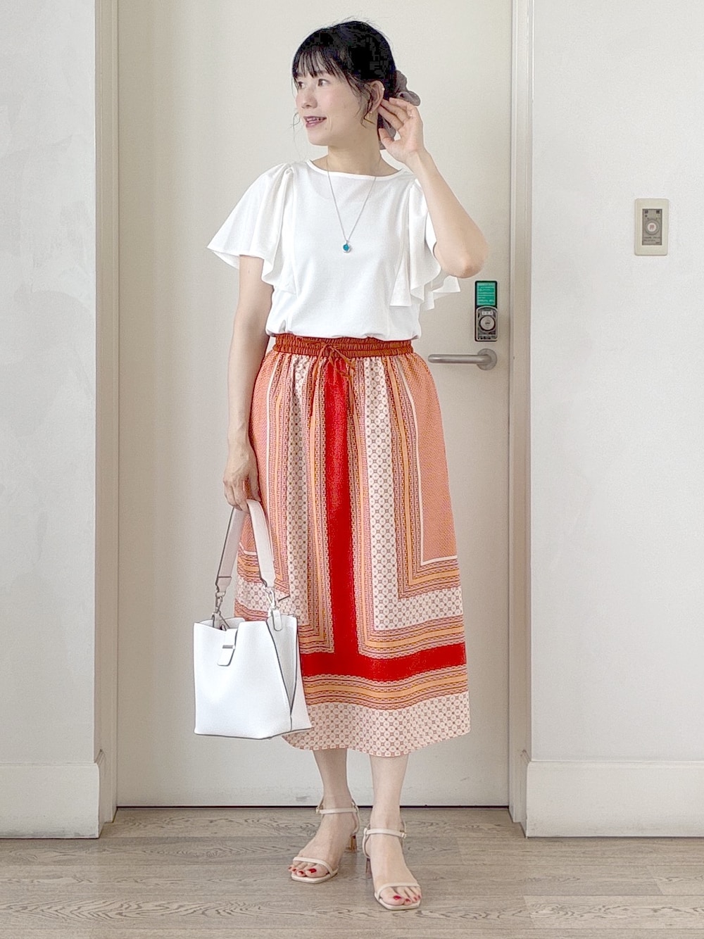 ホワイト系のTシャツ/カットソー、オレンジ系のスカート、ホワイト系のトートバッグを着用したレディースの夏コーディネートの6枚目の写真