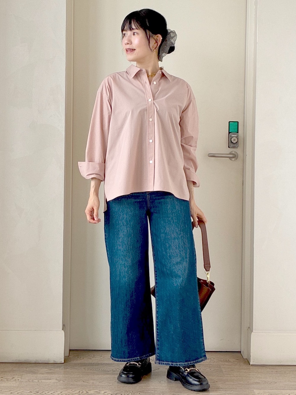 ピンク系のシャツ/ブラウス、ブラック系のニット/セーター、ブルー系のデニムパンツを着用したレディースの秋コーディネートの5枚目の写真