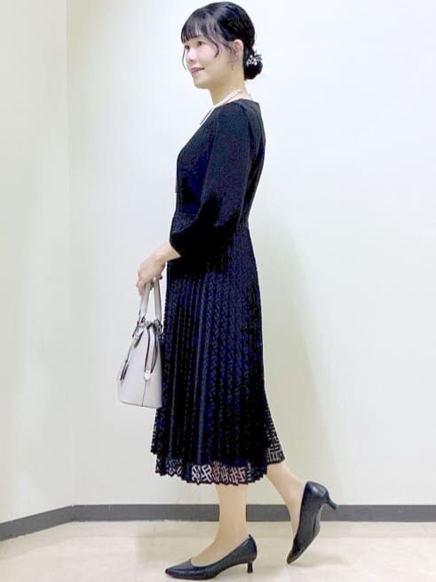 ブラック系のノーカラージャケット、ブラック系のワンピース、ベージュ系のハンドバッグを着用したレディースの冬コーディネートの10枚目の写真