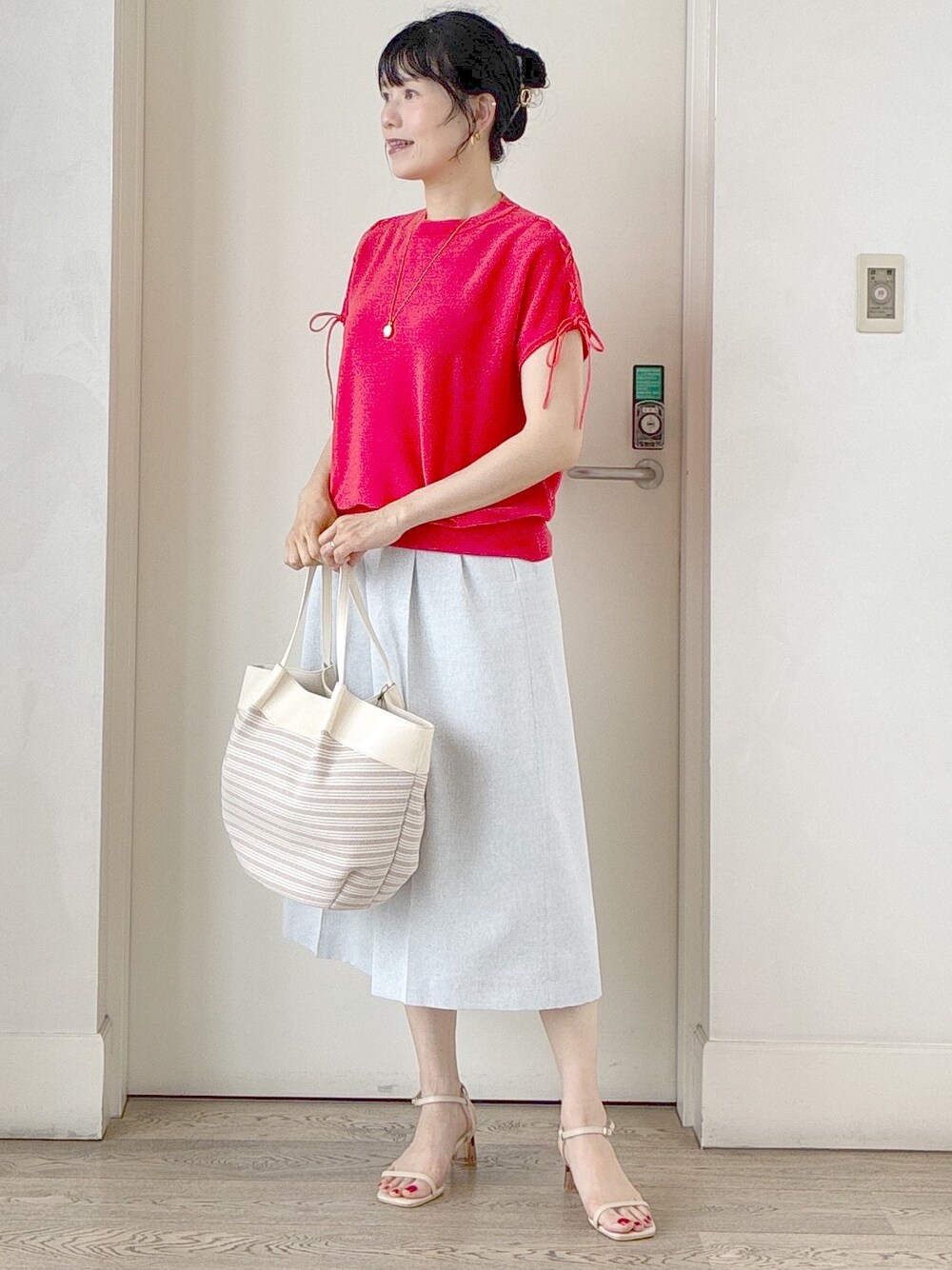 オレンジ系のニット/セーター、グレー系のその他パンツ、ベージュ系のトートバッグを着用したレディースの夏コーディネートの9枚目の写真