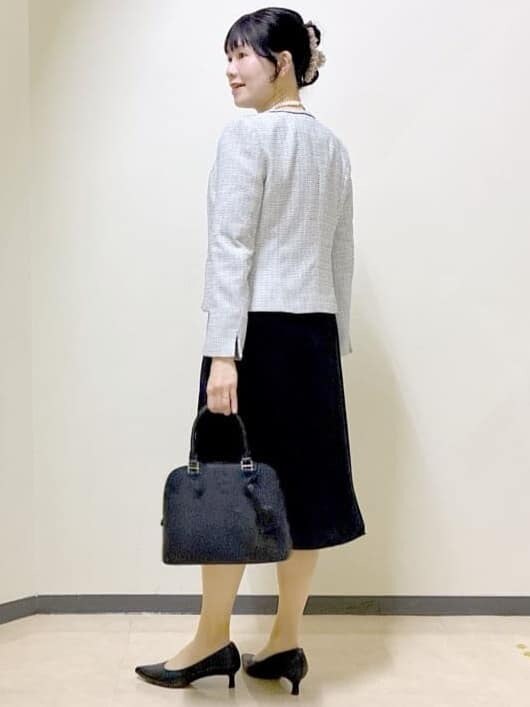 ブラック系のワンピース、ホワイト系のノーカラージャケット、ブラック系のハンドバッグを着用したレディースの冬コーディネートの10枚目の写真