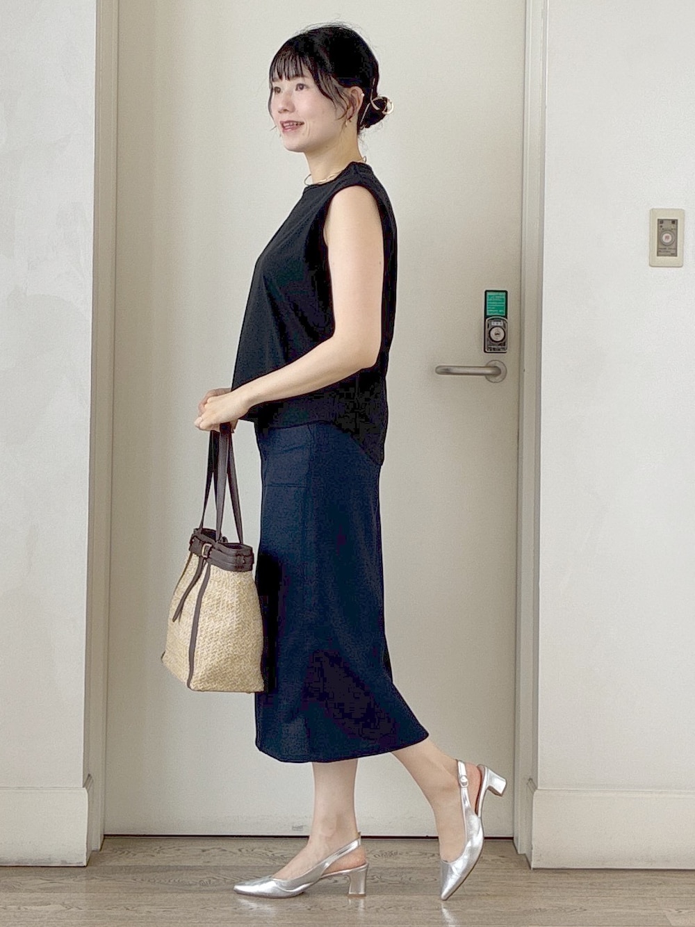 ブラック系のTシャツ/カットソー、ブルー系のスカート、イエロー系のトートバッグを着用したレディースの夏コーディネートの2枚目の写真