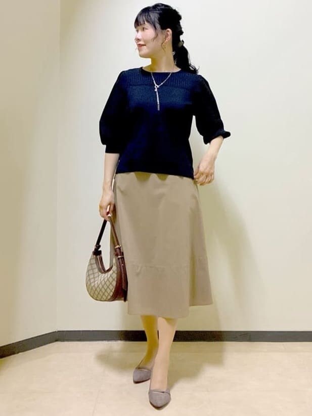 ブルー系のTシャツ/カットソー、イエロー系のスカート、ブラック系のニット/セーターを着用したレディースの秋コーディネートの5枚目の写真