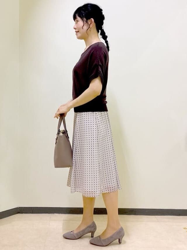 ブラウン系のニット/セーター、ベージュ系のスカート、レッド系のTシャツ/カットソーを着用したレディースの夏コーディネートの2枚目の写真