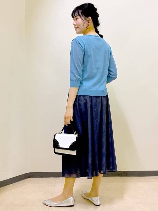 ブルー系のニット/セーター、ブルー系のスカート、ベージュ系のショルダーバッグを着用したレディースの夏コーディネートの4枚目の写真