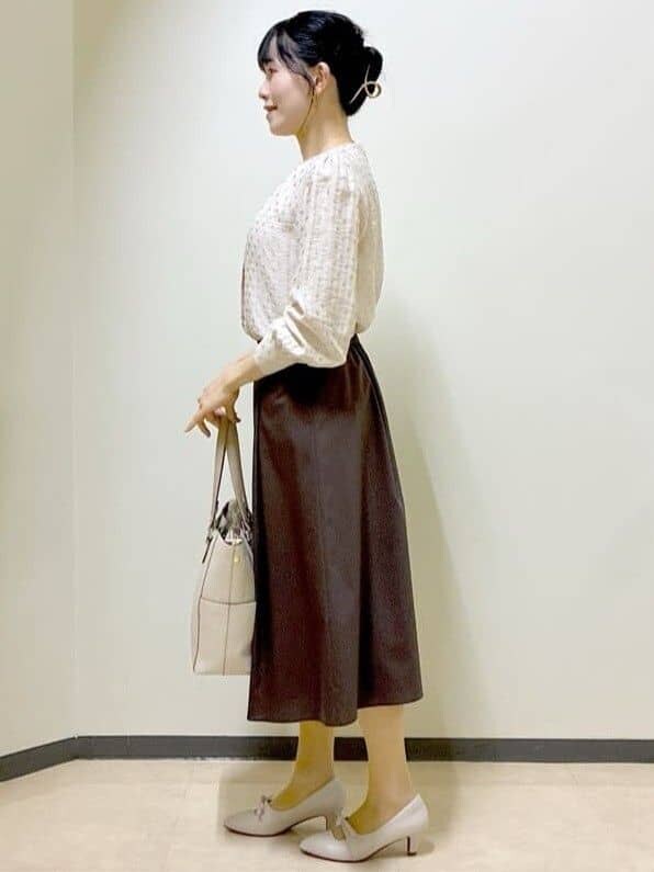 ベージュ系のシャツ/ブラウス、ブラウン系のスカート、ベージュ系のトートバッグを着用したレディースの春コーディネートの2枚目の写真