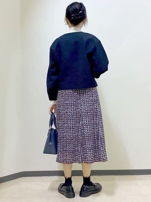 ブルー系のノーカラージャケット、ベージュ系のニット/セーター、ブルー系のスカートを着用したレディースの冬コーディネートの3枚目の写真