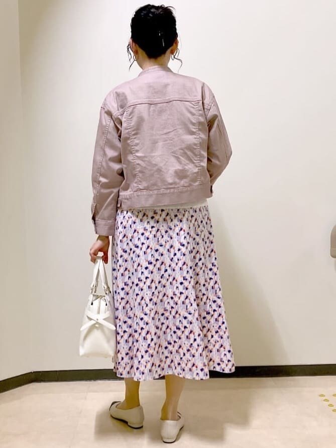 ピンク系のデニムジャケット、ホワイト系のニット/セーター、オレンジ系のスカートを着用したレディースの春コーディネートの3枚目の写真