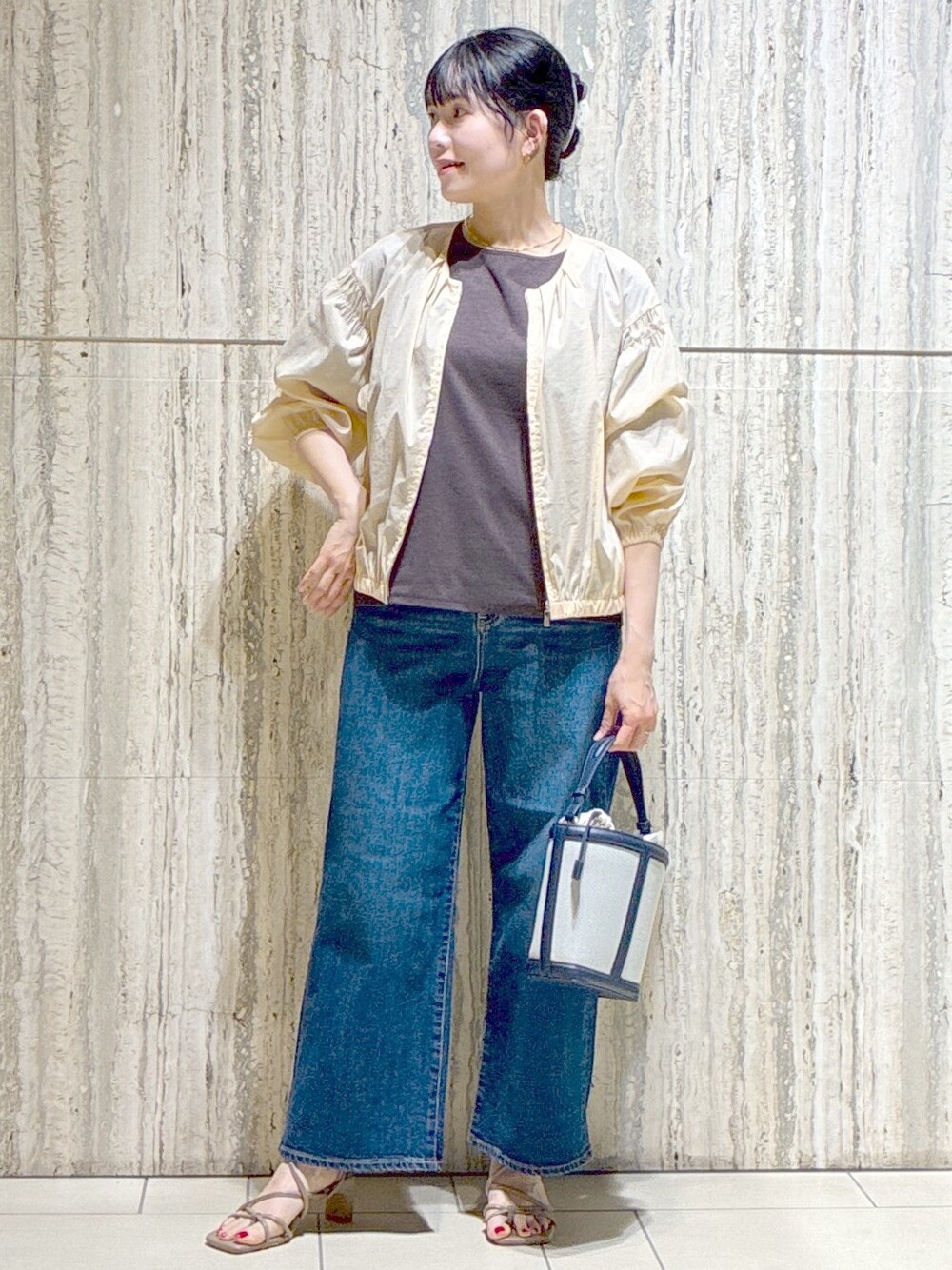 ベージュ系のブルゾン、ブラウン系のTシャツ/カットソー、ブルー系のデニムパンツを着用したレディースの夏コーディネートの6枚目の写真