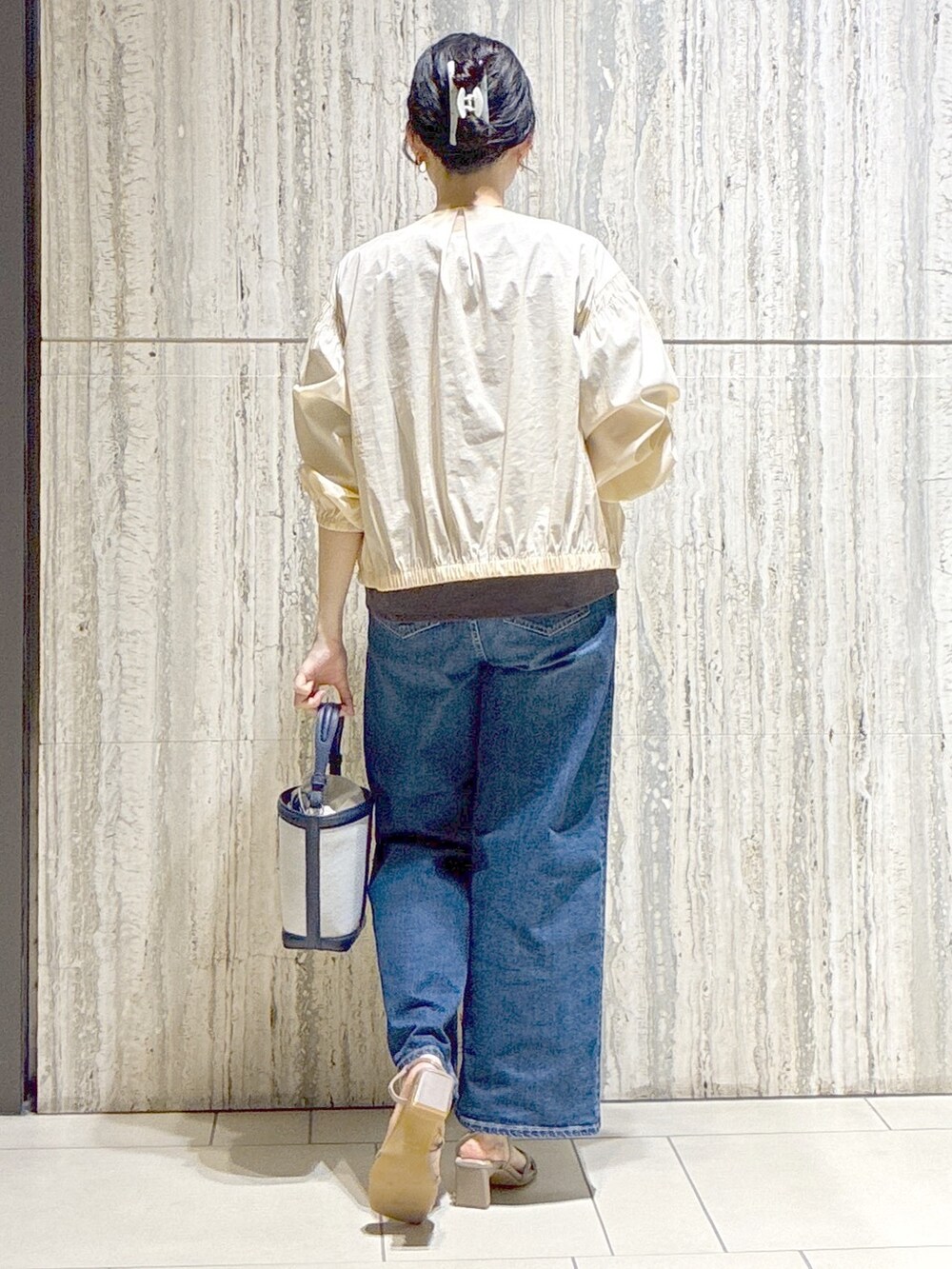 ベージュ系のブルゾン、ブラウン系のTシャツ/カットソー、ブルー系のデニムパンツを着用したレディースの夏コーディネートの3枚目の写真