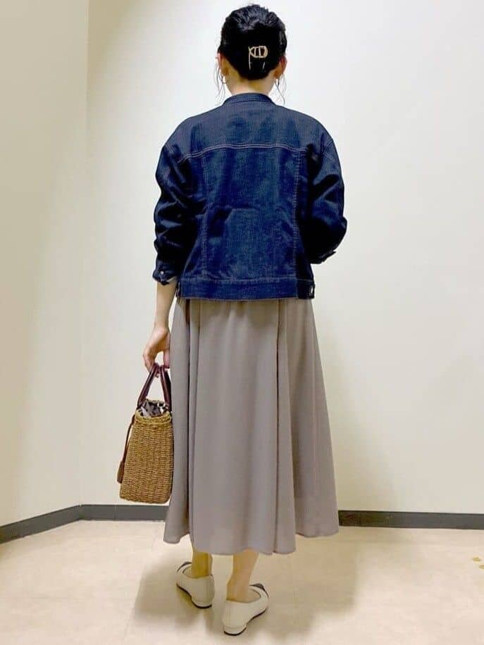 ブルー系のデニムジャケット、ピンク系のニット/セーター、ブラウン系のスカートを着用したレディースの春コーディネートの3枚目の写真
