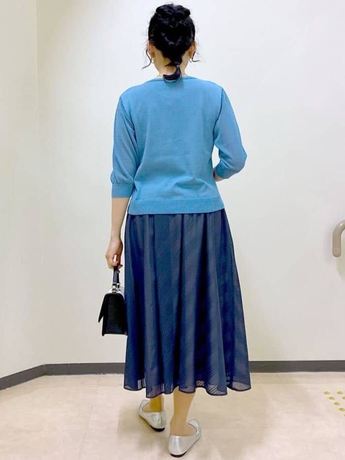 ブルー系のニット/セーター、ブルー系のスカート、ベージュ系のショルダーバッグを着用したレディースの夏コーディネートの3枚目の写真