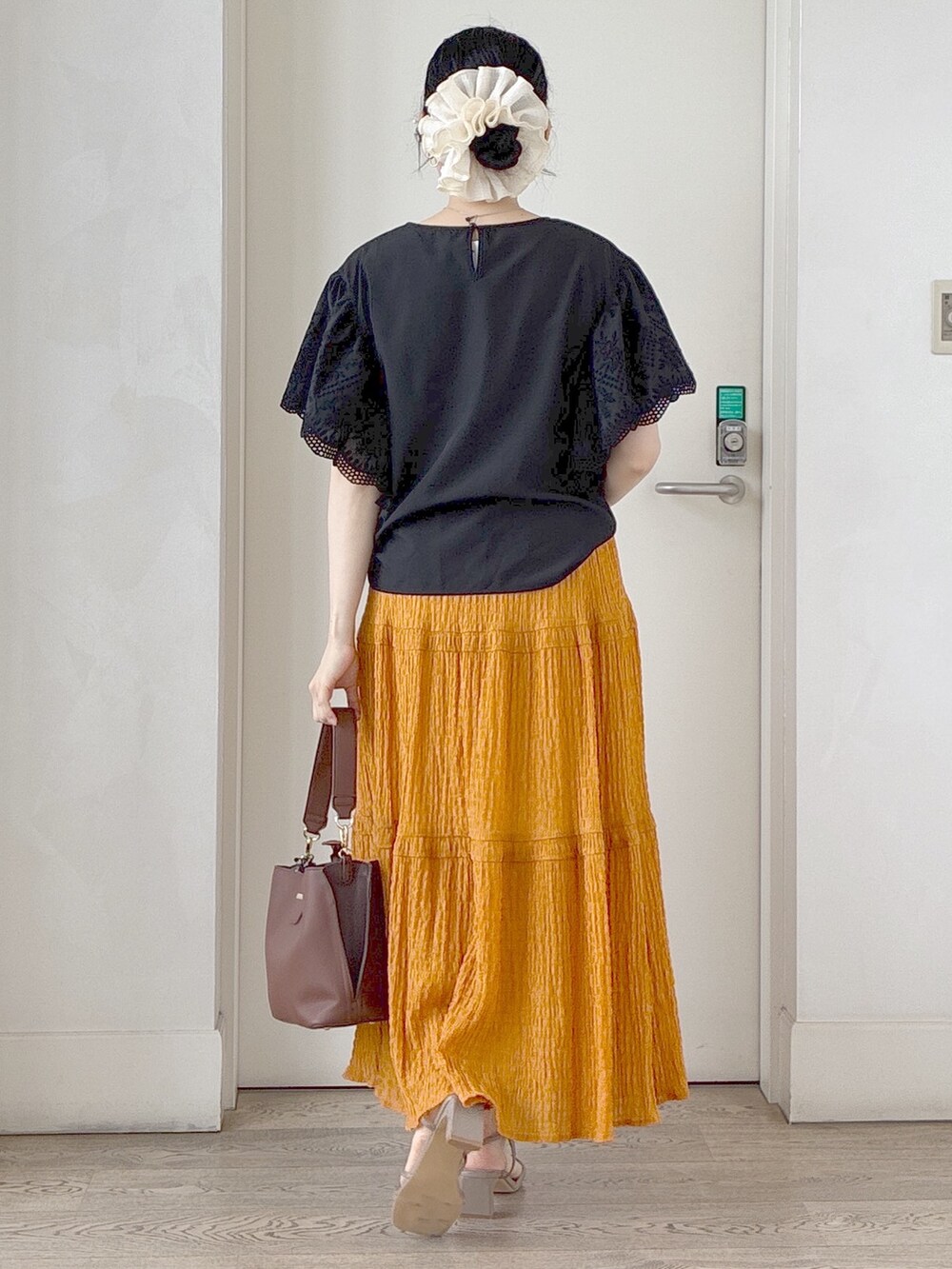 ブラック系のシャツ/ブラウス、オレンジ系のスカート、ベージュ系のブルゾンを着用したレディースの夏コーディネートの3枚目の写真