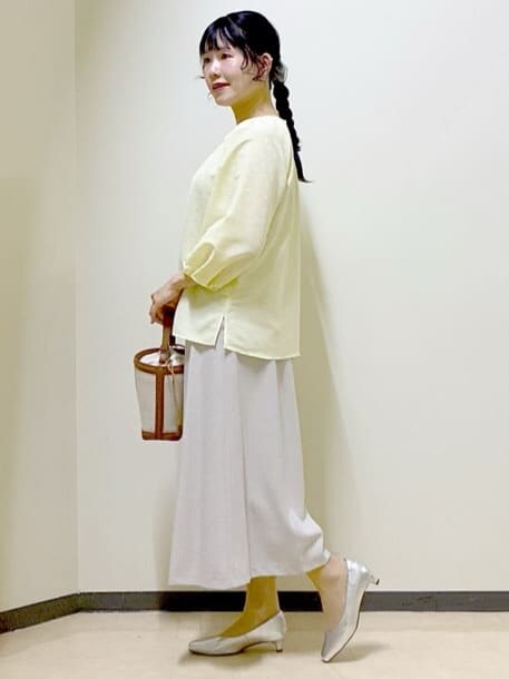 イエロー系のシャツ/ブラウス、シルバー系のパンプス、イエロー系のショルダーバッグを着用したレディースの春コーディネートの2枚目の写真