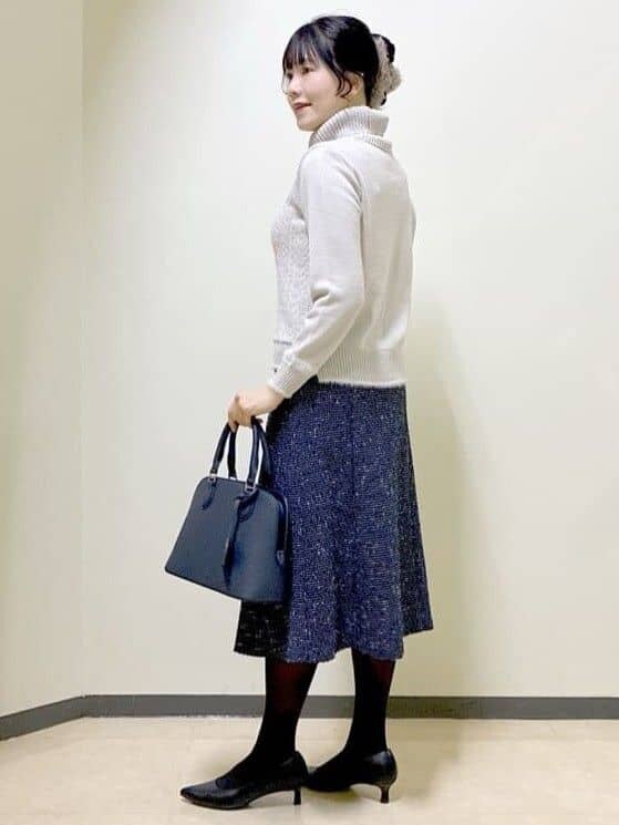 グレー系のニット/セーター、ブルー系のスカート、ブルー系のハンドバッグを着用したレディースの冬コーディネートの4枚目の写真