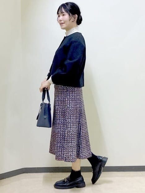 ブルー系のノーカラージャケット、ベージュ系のニット/セーター、ブルー系のスカートを着用したレディースの冬コーディネートの2枚目の写真