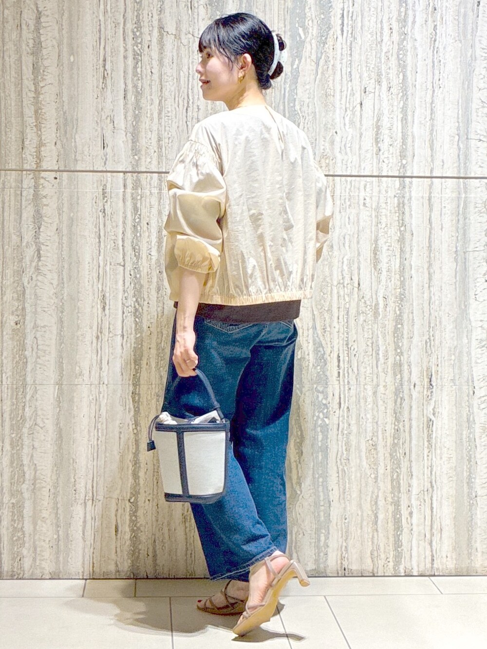 ベージュ系のブルゾン、ブラウン系のTシャツ/カットソー、ブルー系のデニムパンツを着用したレディースの夏コーディネートの4枚目の写真