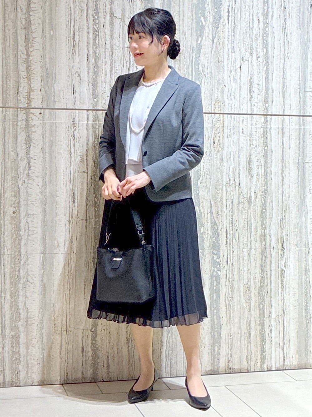 グレー系のテーラードジャケット、ブルー系のスカート、ブラック系のトートバッグを着用したレディースの秋コーディネートの7枚目の写真