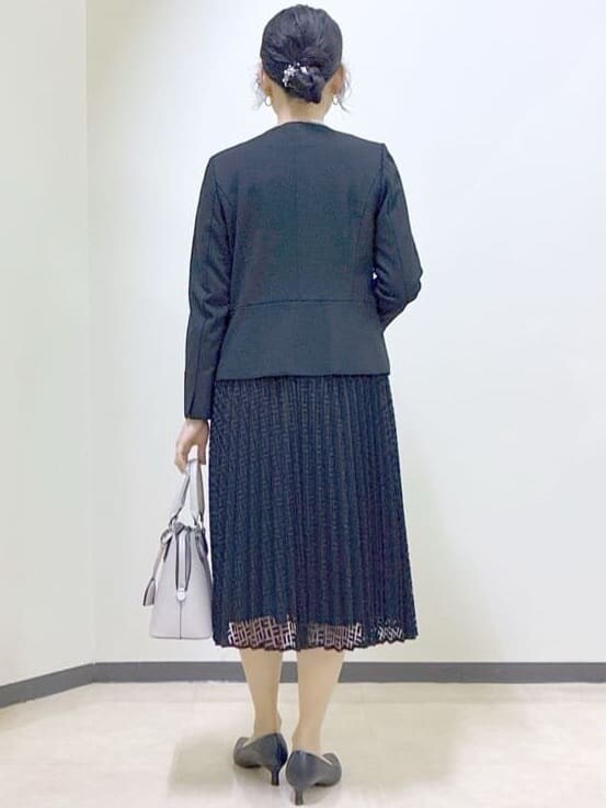 ブラック系のノーカラージャケット、ブラック系のワンピース、ベージュ系のハンドバッグを着用したレディースの冬コーディネートの3枚目の写真