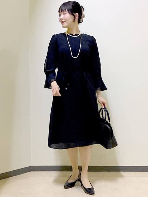 ブラック系のワンピース、ホワイト系のノーカラージャケット、ブラック系のハンドバッグを着用したレディースの冬コーディネートの8枚目の写真