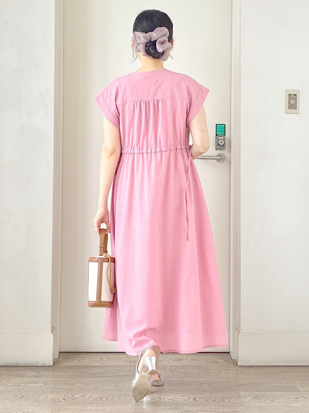 ピンク系のワンピース、ベージュ系のタンクトップ、ホワイト系のカーディガン/ボレロを着用したレディースの夏コーディネートの3枚目の写真