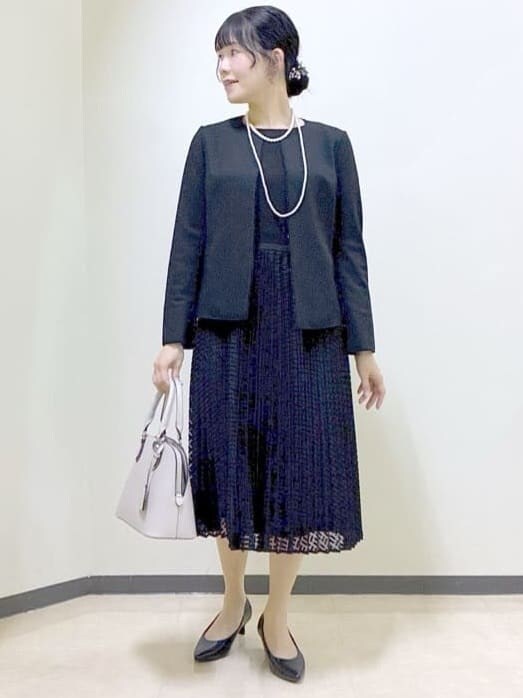 ブラック系のノーカラージャケット、ブラック系のワンピース、ベージュ系のハンドバッグを着用したレディースの冬コーディネートの6枚目の写真