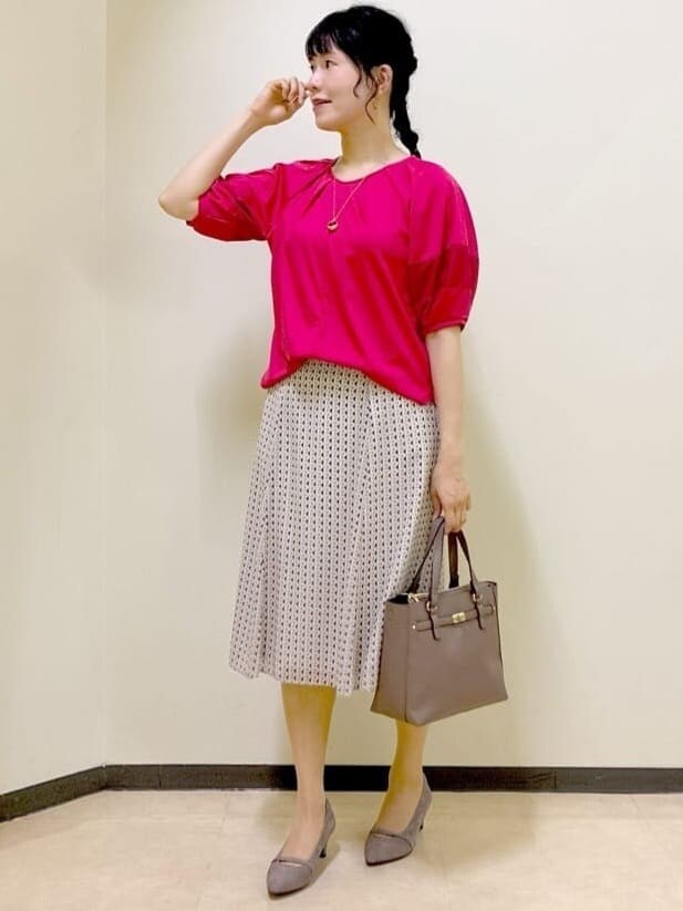 レッド系のTシャツ/カットソー、ベージュ系のスカート、ブラウン系のニット/セーターを着用したレディースの秋コーディネートの5枚目の写真