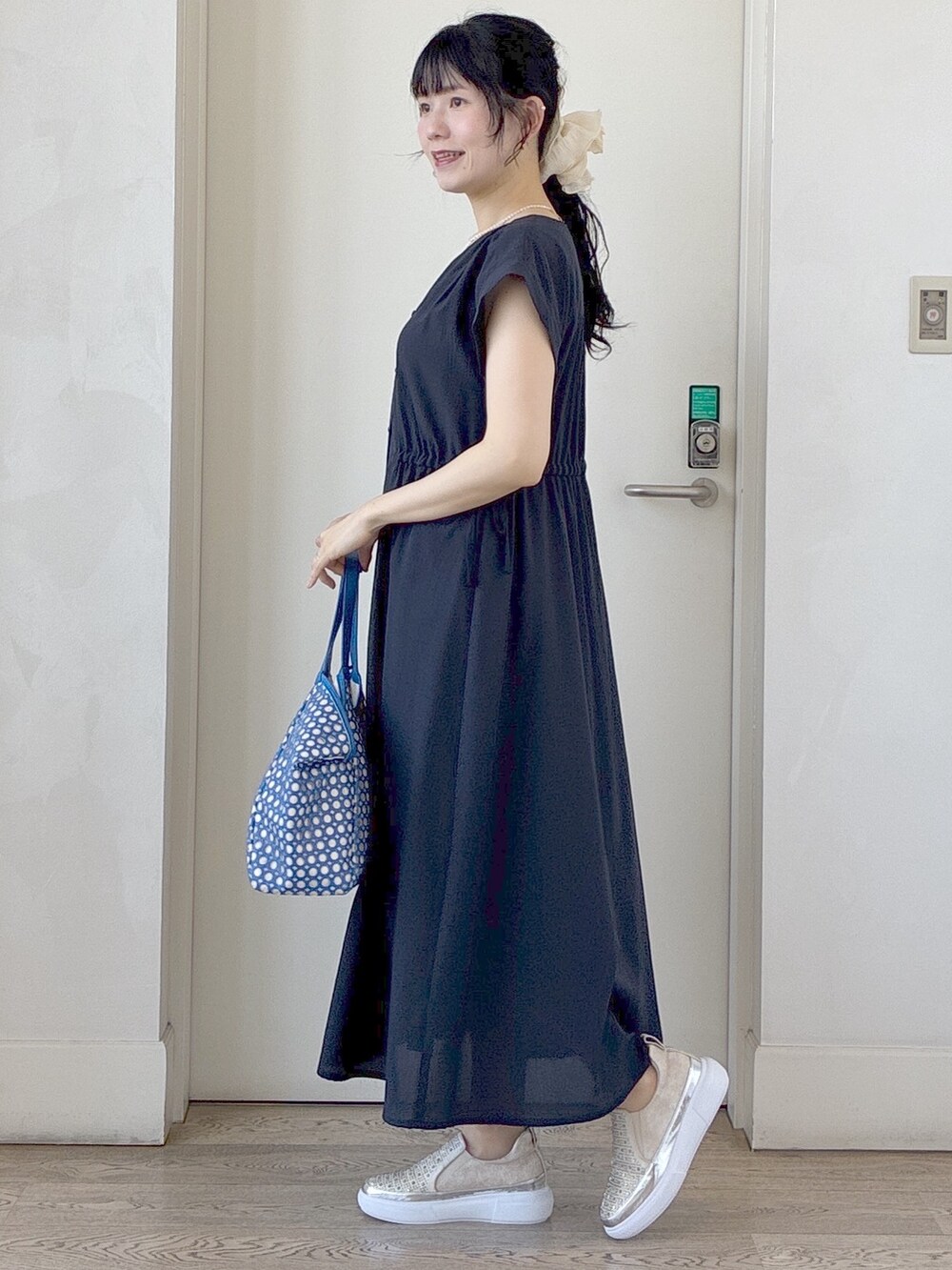 ブルー系のワンピース、ベージュ系のタンクトップ、ブルー系のブルゾンを着用したレディースの春コーディネートの2枚目の写真