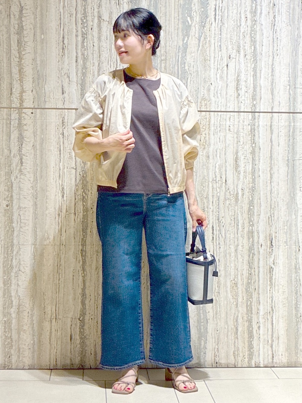 ベージュ系のブルゾン、ブラウン系のTシャツ/カットソー、ブルー系のデニムパンツを着用したレディースの夏コーディネートの5枚目の写真