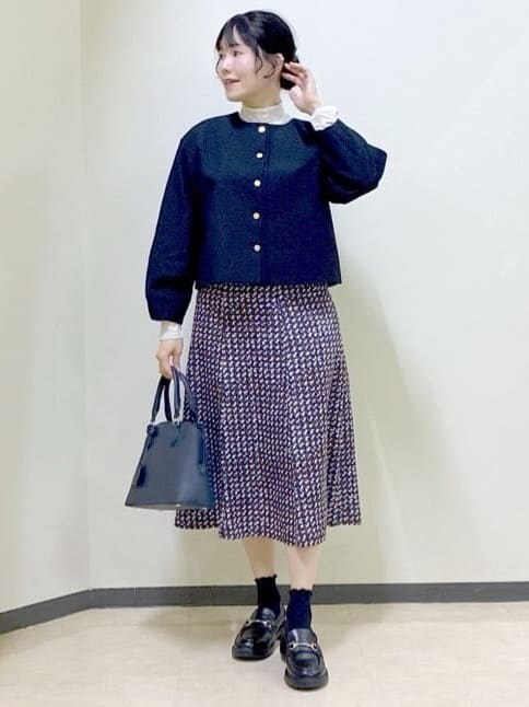 ブルー系のノーカラージャケット、ベージュ系のニット/セーター、ブルー系のスカートを着用したレディースの冬コーディネートの5枚目の写真
