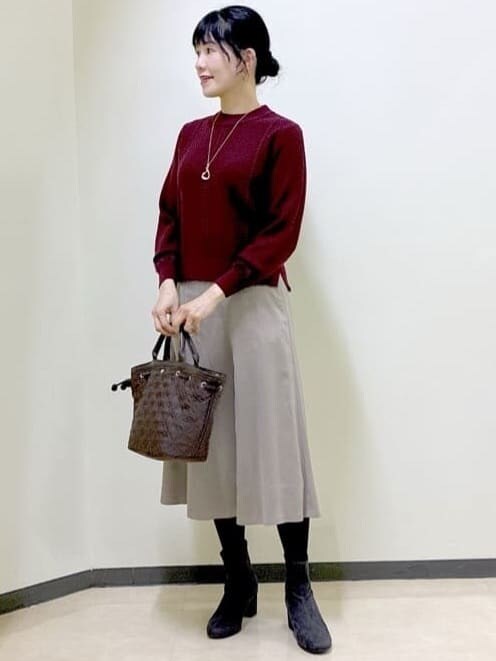 レッド系のニット/セーター、ベージュ系のスカート、ブラック系のダウンジャケット/コートを着用したレディースの秋コーディネートの6枚目の写真