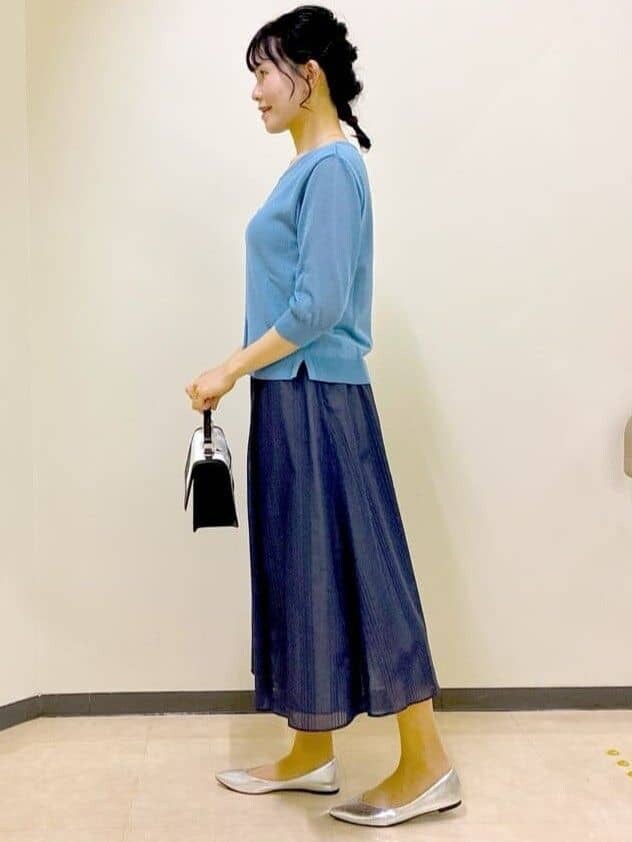 ブルー系のニット/セーター、ブルー系のスカート、ベージュ系のショルダーバッグを着用したレディースの夏コーディネートの2枚目の写真